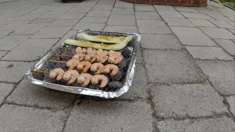 Locked off view of disposable mini BBQ grill with Zucchini and Shrimp skewers SLOW MOTION