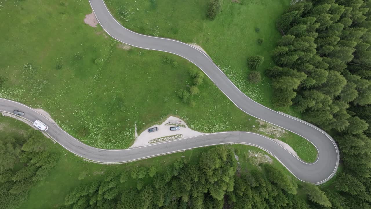 una perspectiva aérea captura varios coches serpenteando a través de las carreteras boscosas cerca del paso de selva en las montañas dolomitas, trentino, tirol del sur, italia