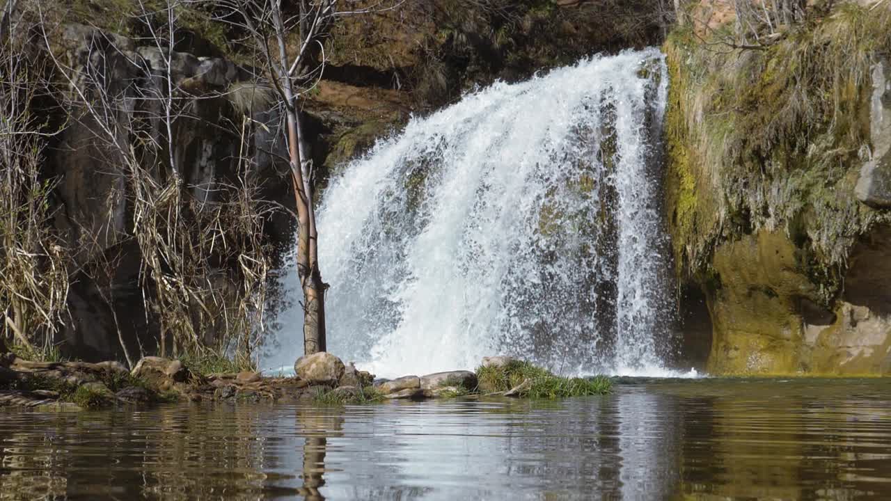Una grande cascata a picco sulla scogliera sullo sfondo, circondata da una montagna in una giornata di sole