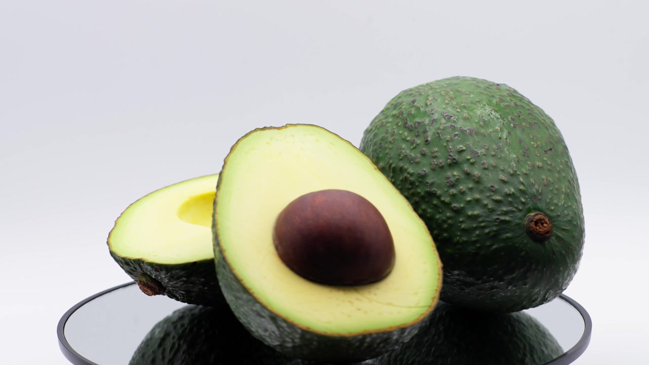 CLOSE UP SHOT OF AVOCADOS ROTATING WITH A WITHE BACKGOROUND