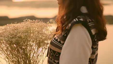 silhouette of girl holding the tiny flowers in hands under sunset rim light