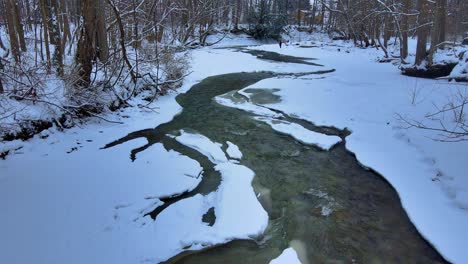 Aerial-drone-footage-of-a-partially-frozen-creek-during-winter-in-western-new-York-state-after-fresh-snowfall