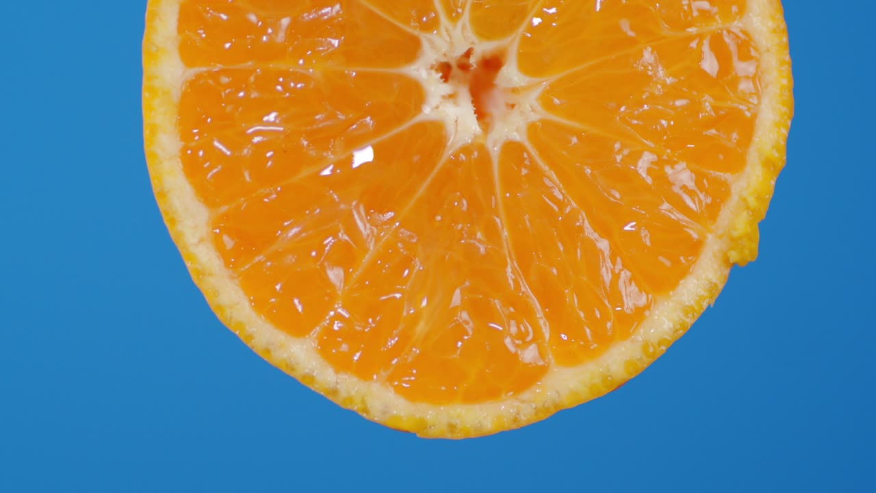 With a round piece of Mandarin falling drops of juice.