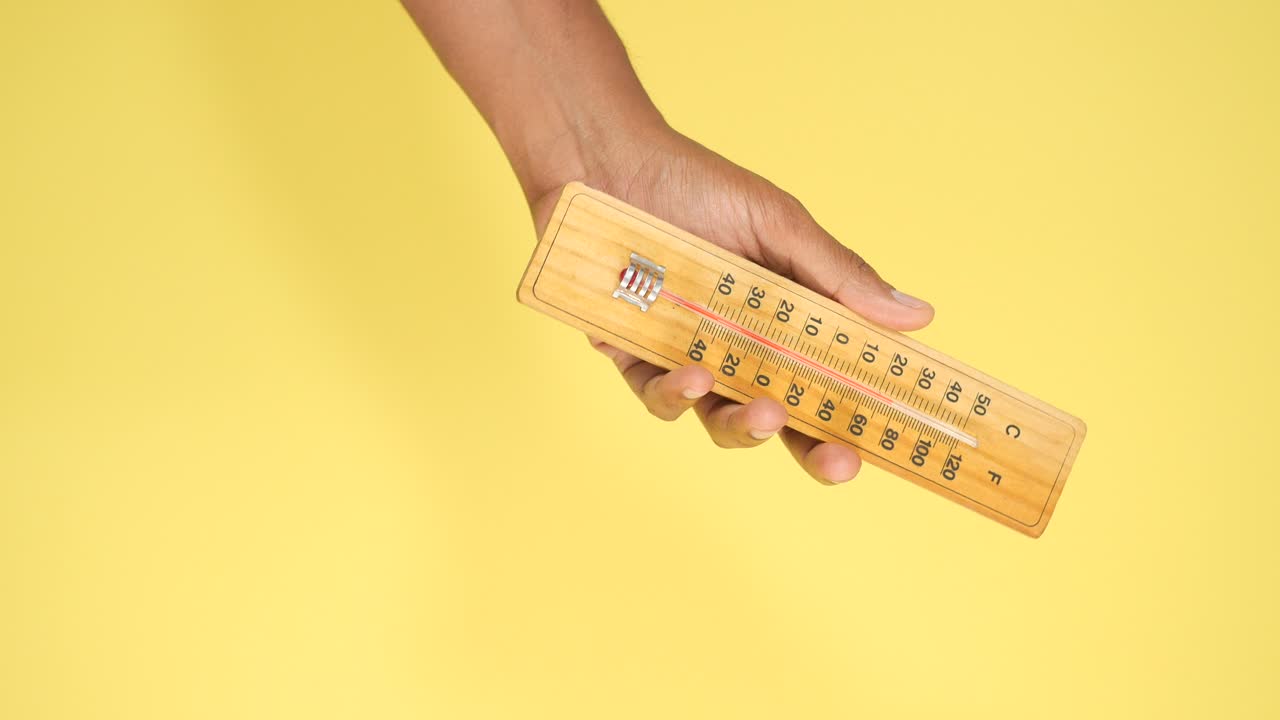mano con un termómetro de madera