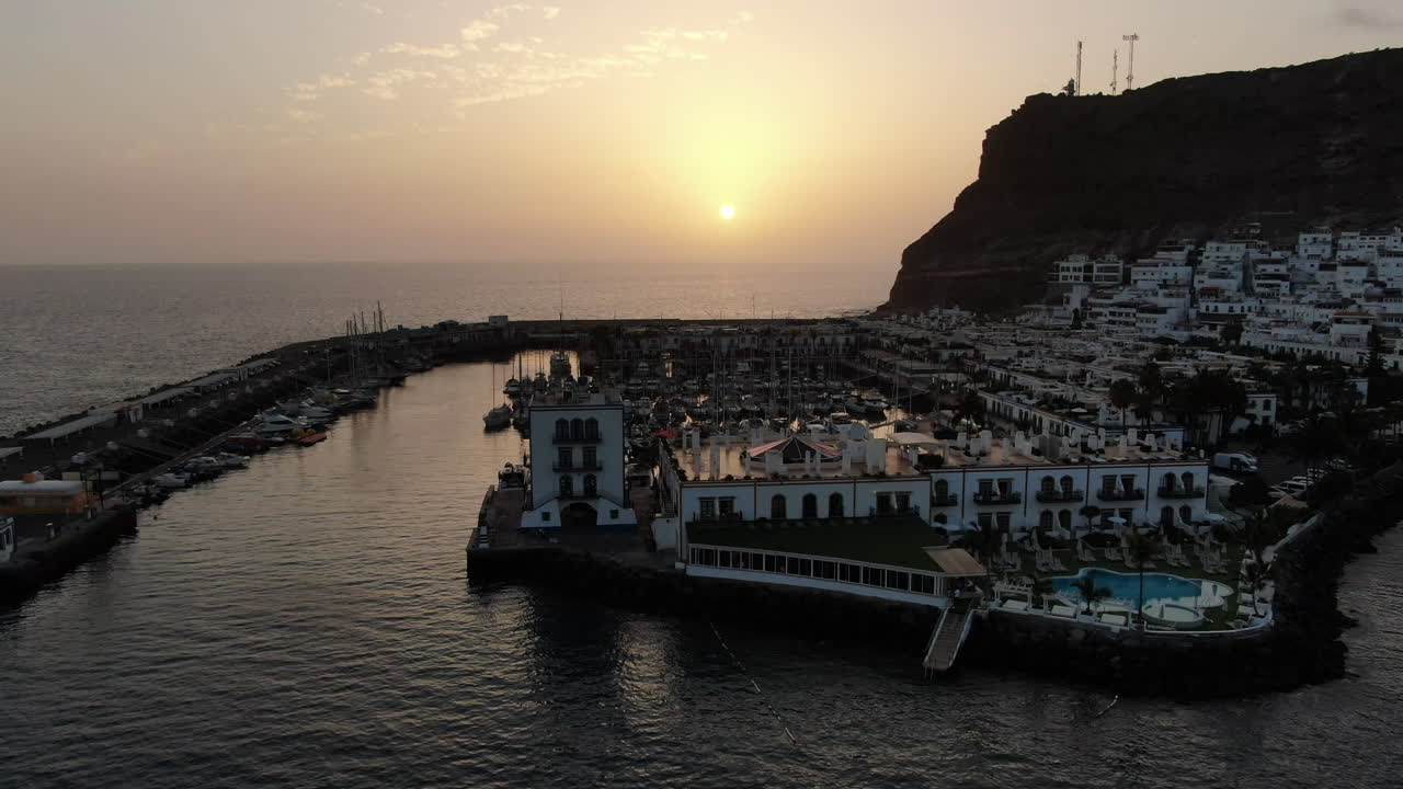 puerto de mogan: vista aérea con movimiento de zoom y durante la puesta de sol de la ciudad de puerto de mogan con hermosos colores