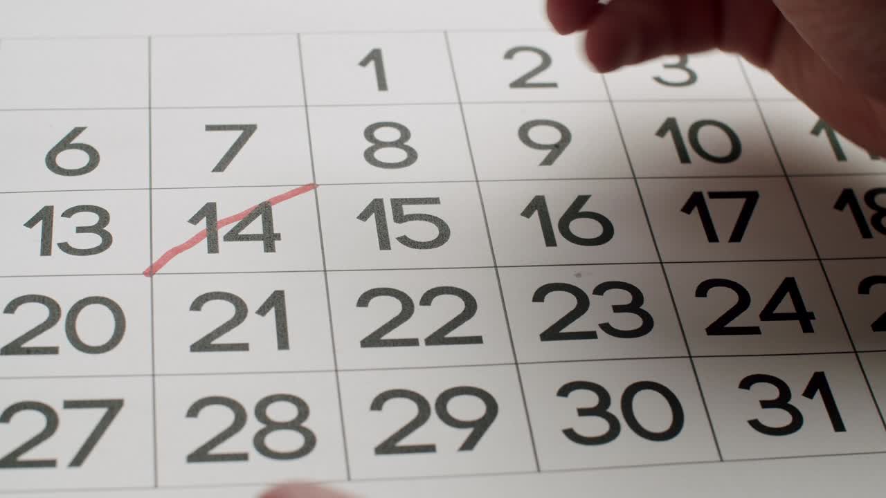 la mano del hombre escriba el día 23 en el calendario de papel usando un bolígrafo rojo.