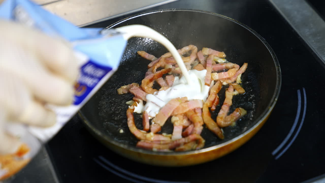 Frying bacon pieces in a pan. Crispy pieces of delicious bacon are fried in a hot skillet. Unhealthy food.