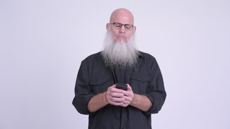 mature bald bearded man using phone