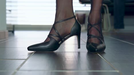 showing elegant stiletto high heels in front of the camera placed on the floor