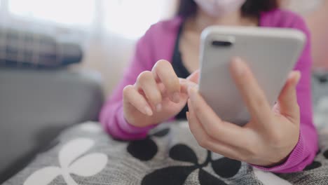 una mujer en primer plano sentada en un sofá sosteniendo un teléfono inteligente para comprar en línea en casa