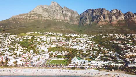 antena moviéndose a lo largo de la rica costa y elegantes casas de camps bay cape town sudáfrica con el fondo de las montañas de los doce apóstoles