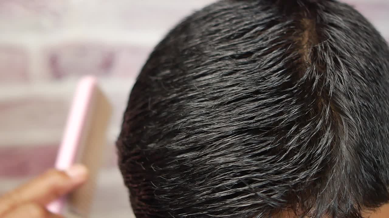 Side view of man styling hair with comb on black background