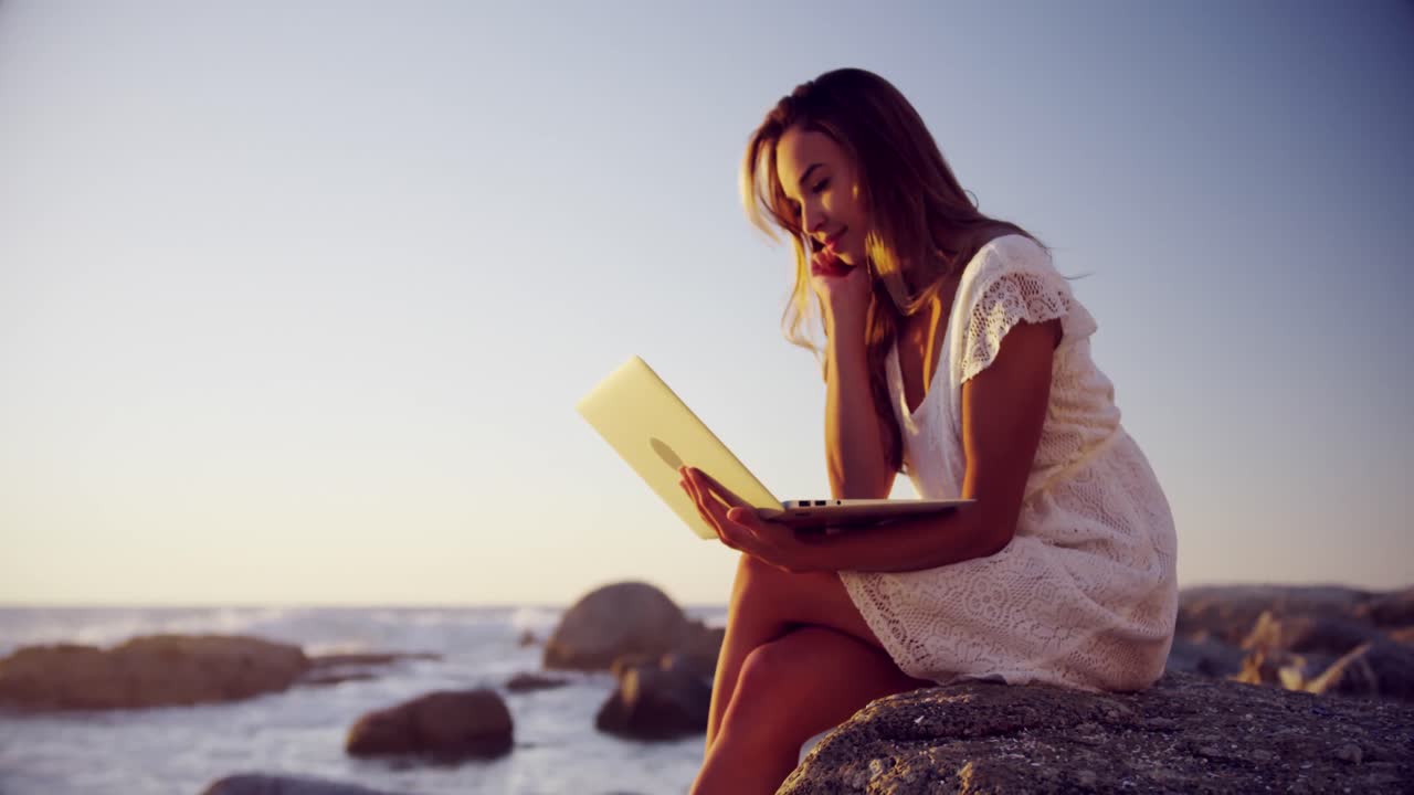 Donna che utilizza un portatile sulla spiaggia 4K
