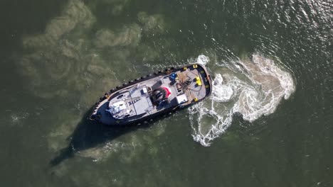 a top down, aerial view over a tugboat on a sunny day in the east rockaway inlet in queens, ny