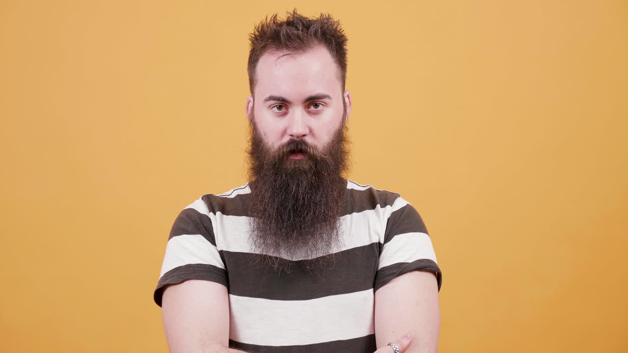 Portrait of a bearded man in a striped shirt on a yellow background