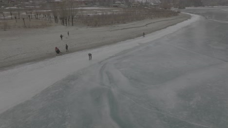 aerial orbit motion view of person skating on edge of frozen khalti lake at ghizer valley