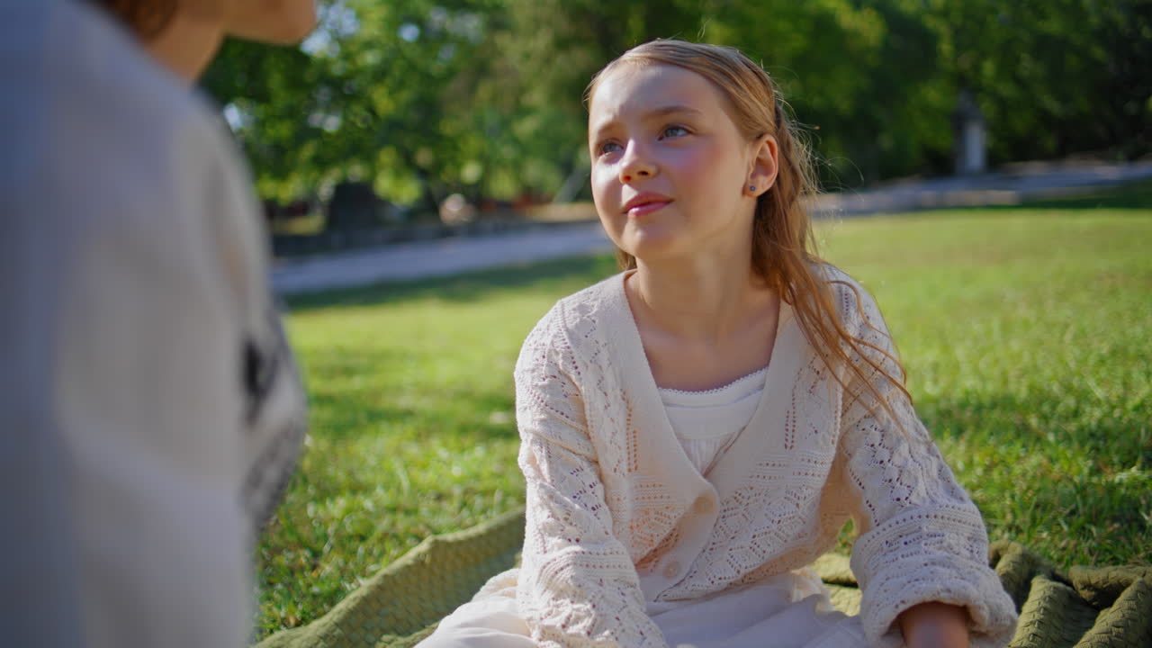 Talking girl sitting grass having conversation with mother at sunny day closeup