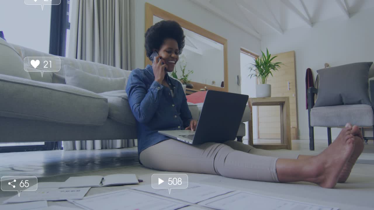 Woman sitting at home sorting work docs while using laptop alerts rising around after tapping phone