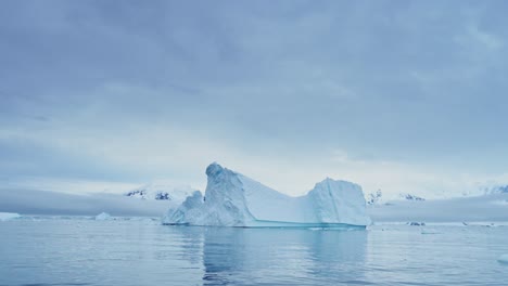 Gran-Puesta-De-Sol-Del-Paisaje-Marino-Del-Iceberg-De-La-Antártida,-Grandes-Icebergs-Azules-Masivos-Con-Formas-Asombrosas-Y-Nubes-Dramáticas-Y-Cielo-En-El-Paisaje-Invernal-Del-Amanecer-En-La-Península-Antártica-En-Una-Escena-Helada