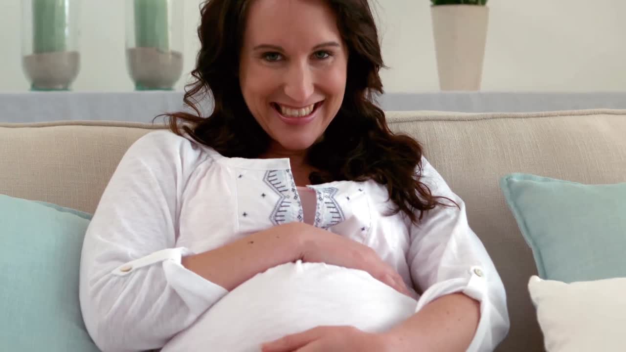 mujer embarazada sentada en el sofá tocando su vientre