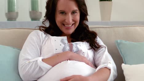 Pregnant-woman-sitting-on-sofa-touching-her-belly