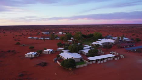 Drohnenvideo-Einer-Lodge-Mitten-In-Der-Afrikanischen-Wüste-Mit-Vielen-Kleinen-Wohnungen-Und-Grünen-Anlagen-Im-Sonnenuntergang