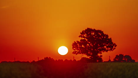 Salida-De-La-Luna-Contra-El-Cielo-Rojo-Brillante-Del-Atardecer-Sobre-Los-Campos-Rurales