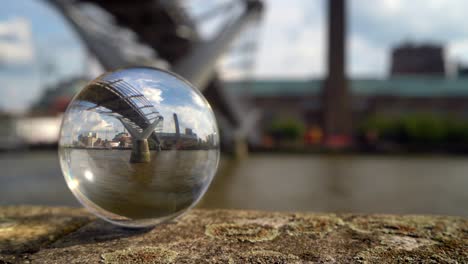 tate modern art gallery and the millennium bridge refracted in a glass sphere