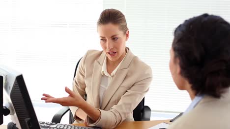 Smiling-businesswoman-showing-something-to-her-colleague