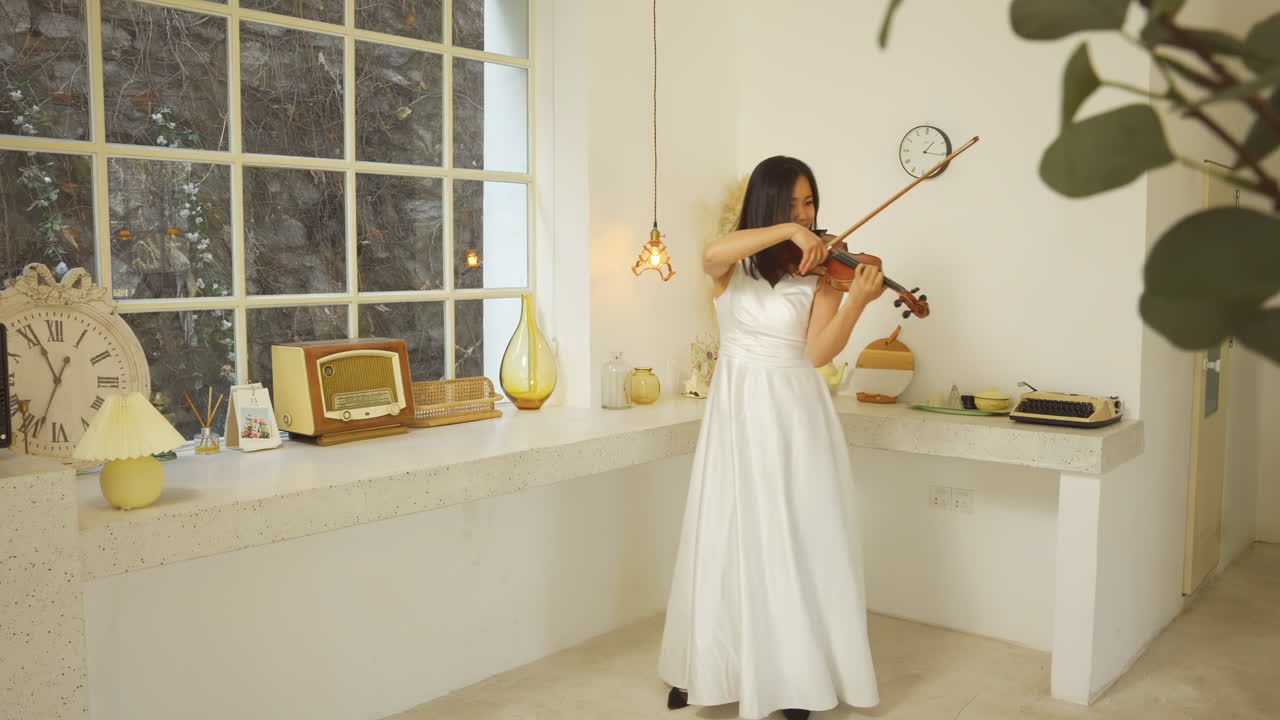 Light room with musician woman with long hair playing melody on violin classic old style. Masterfully musician rehearsing her part before serene performance with vintage decor classical music
