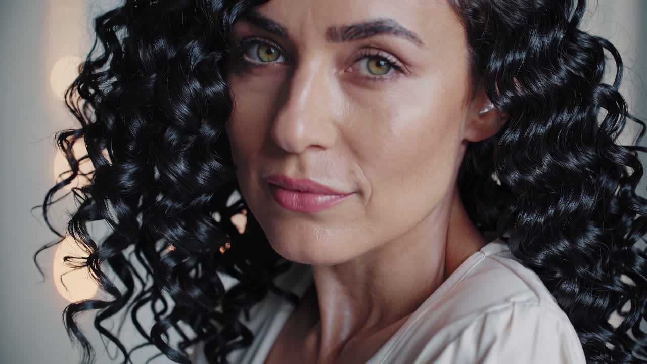 Close-up video shot of a woman with curly hair, capturing her serene expression