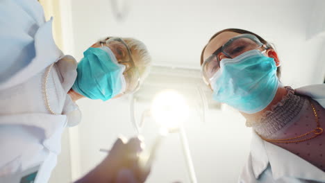 dentists wearing surgical masks looking down at patient