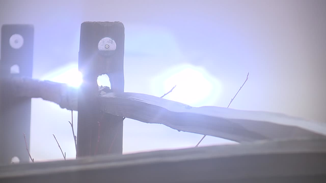 OLD FENCE IN THE FOG AS CARS DRIVE BY