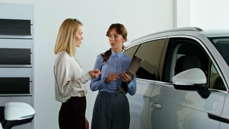 women discussing a car purchase in a showroom