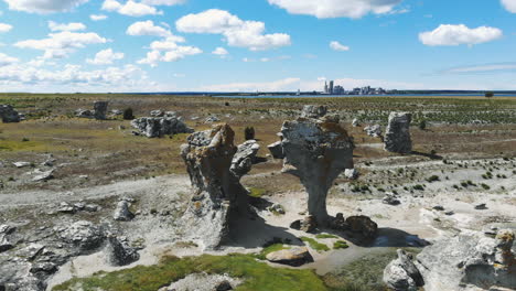 pair of odd rock formations on flat land with cityscape in background