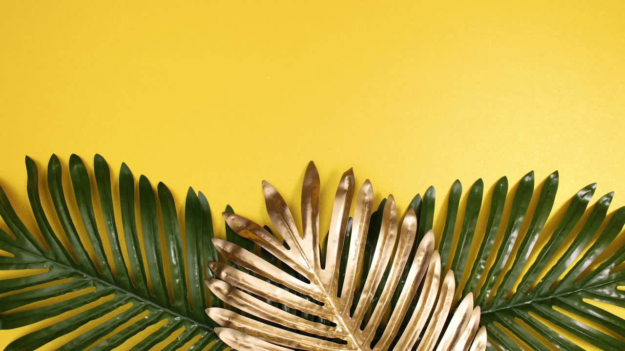 el oro tropical y el arreglo de hojas de palma verde aparecen sobre un fondo dorado.