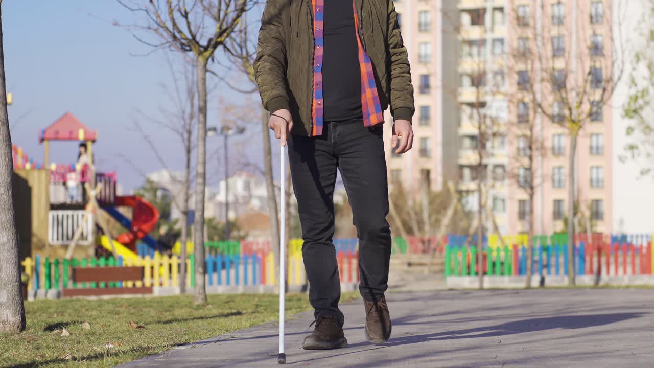 Uomo cieco con bastone bianco che cammina sulla strada.