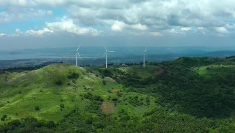 pililla wind mills between green mountains of philippines rizal. cloudy day on asian island. production of eco friendly energy with wind. drone wide shot.