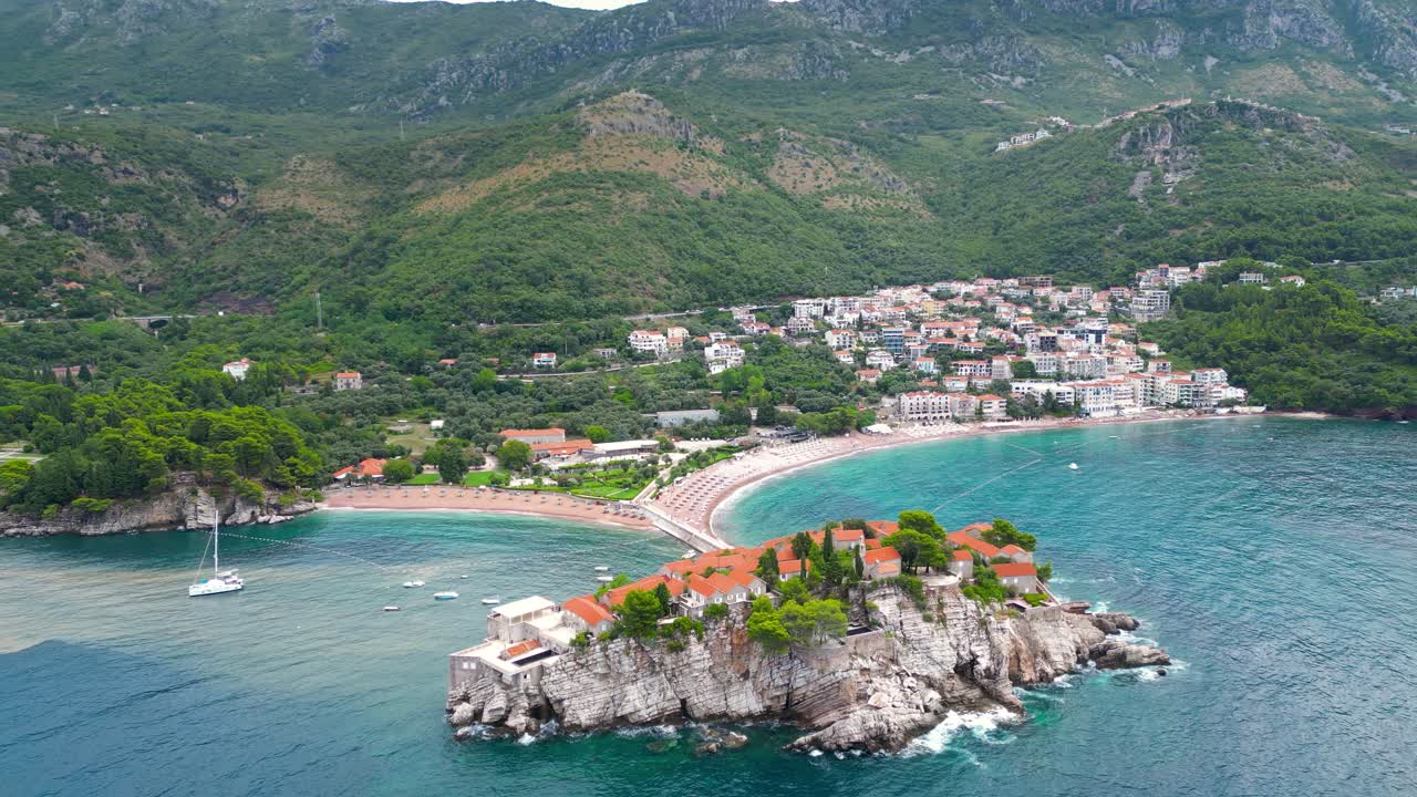 Sveti Stefan Island, aerial perspective. Drone circling arround the island. Famous and luxury travel destination in Montenegro. Boats in the middle of the bay.