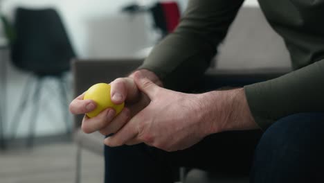 Unrecognizable-man-sitting-in-clinic-waiting-room-and-squeezing-a-stress-ball