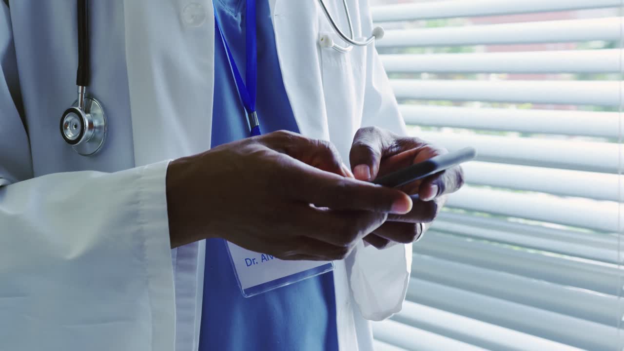 Mid section of African American male doctor using mobile phone in hospital 4k