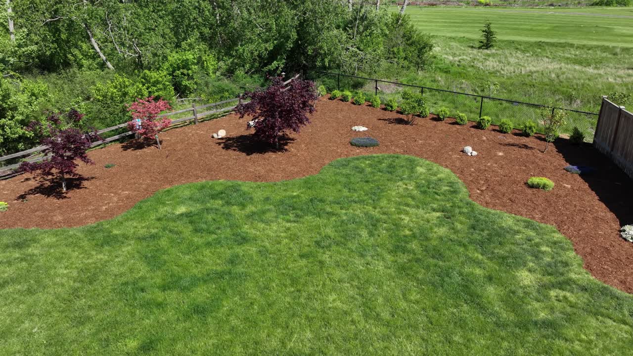 toma aérea empujando a través de un patio trasero con una capa fresca de corteza de prevención de malezas