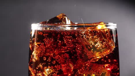 cola with ice and bubbles in glass slow motion.