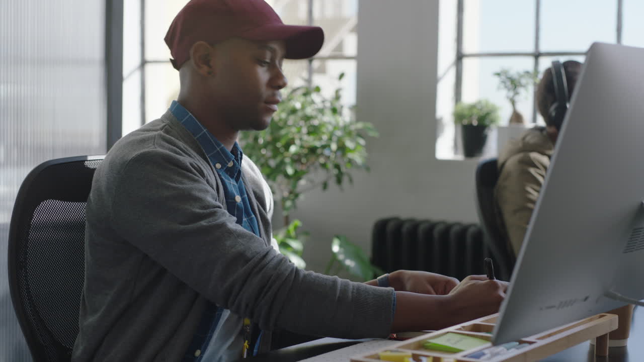 happy african american business man reading corporate documents brainstorming ideas writing notes using computer planning strategy enjoying successful career in modern startup communication company