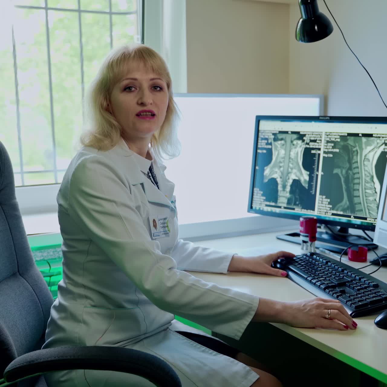 Doctor Working In Monitoring Room. Professional technical doctor sitting at desk with multiple displays in hospital