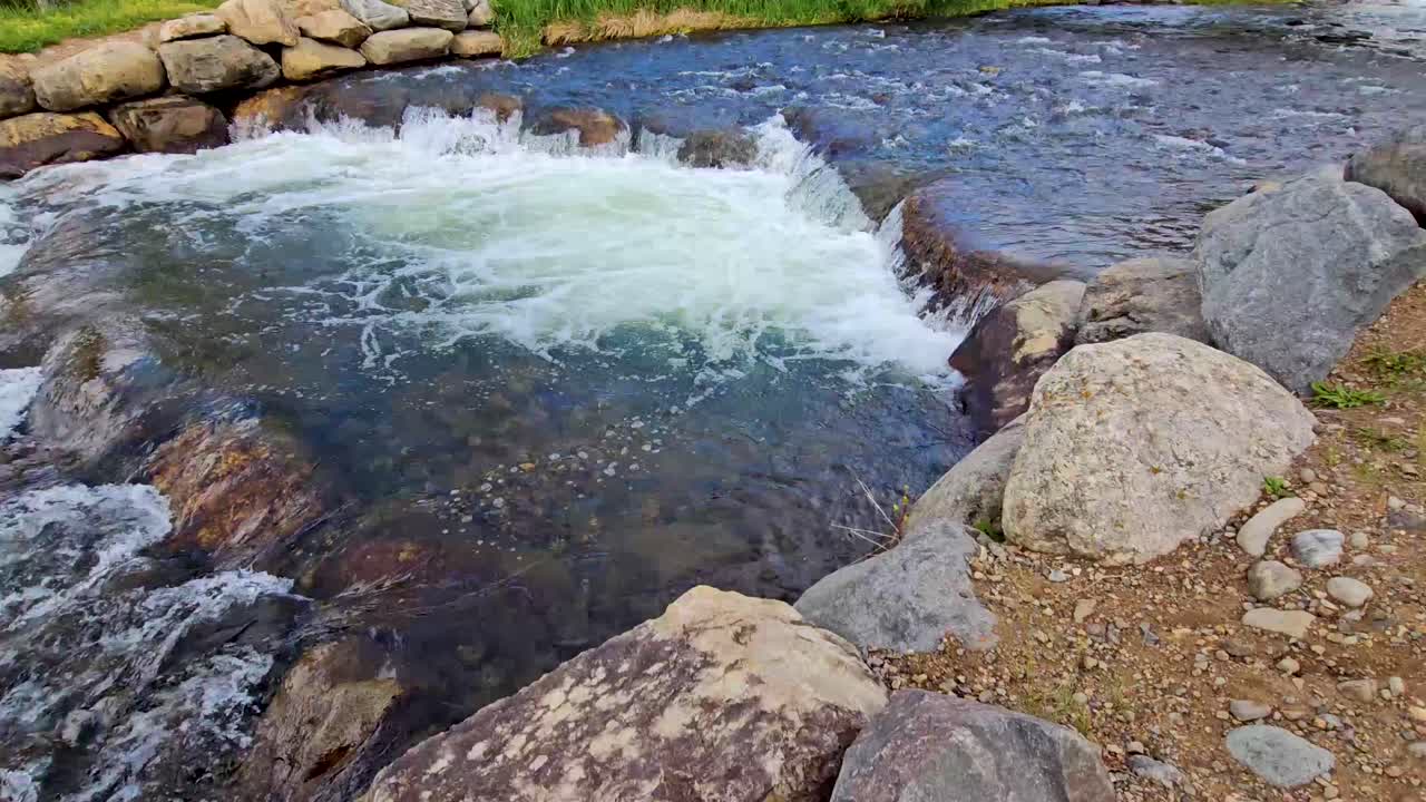 Handheld video of a stream in Breckenridge Texas. A small set of rapid create a small waterfall over rocks.