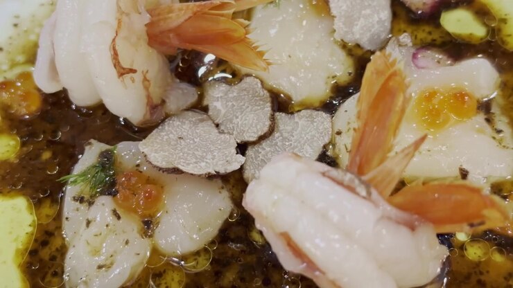 Close-up of shrimp and scallop carpaccio with delicate gourmet dressing, elegantly plated for a refined seafood dining experience.