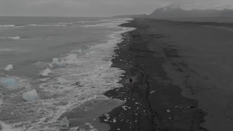 Aerial-Shot-of-a-Lone-Tourist-on-Black-Sand-Beach