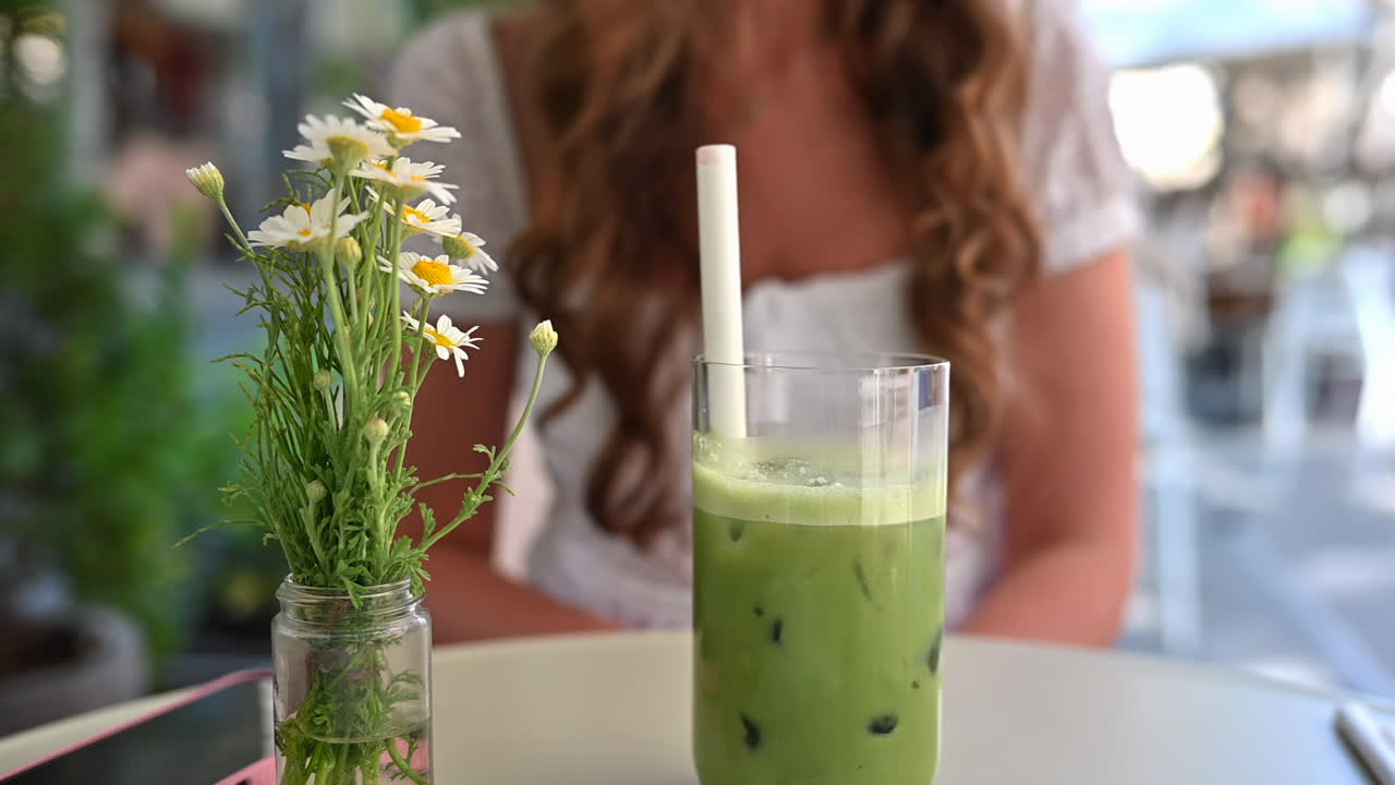 Woman drinking green cold matcha tea at a restaurant terrace