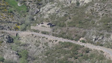 flight-with-a-drone-visualizing-a-mountain-road-and-circulating-downhill-are-a-group-of-cyclists-in-line-letting-themselves-be-carried-away-by-inertia-in-moments-port-of-Mijares-Avila-Spain